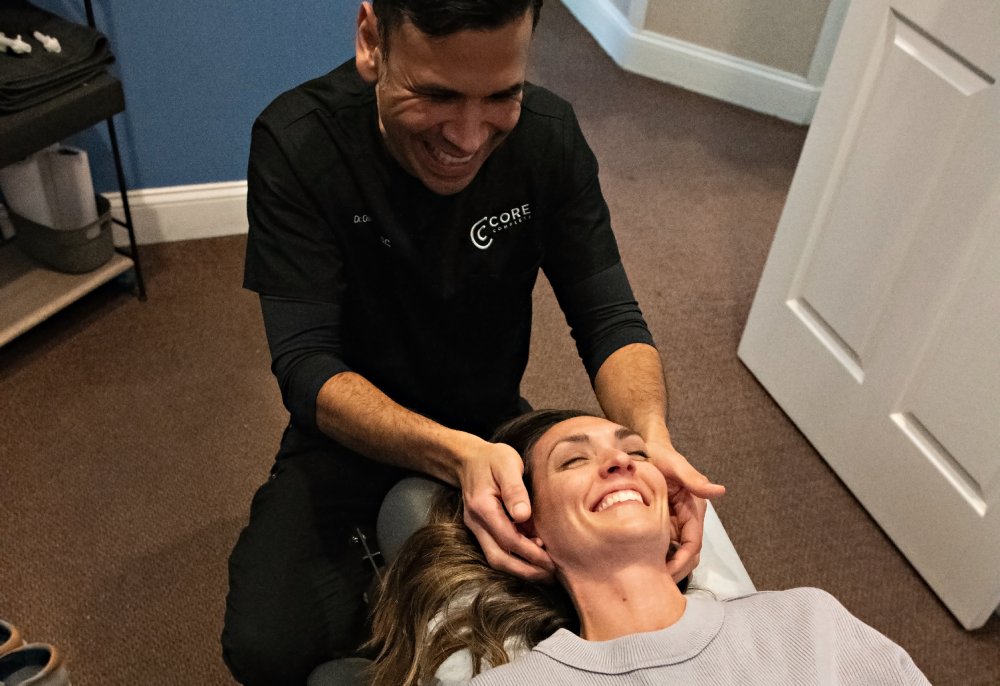 Dr. Oscar Posada performing a gentle adjustment with a smiling patient at CoreNeuro
